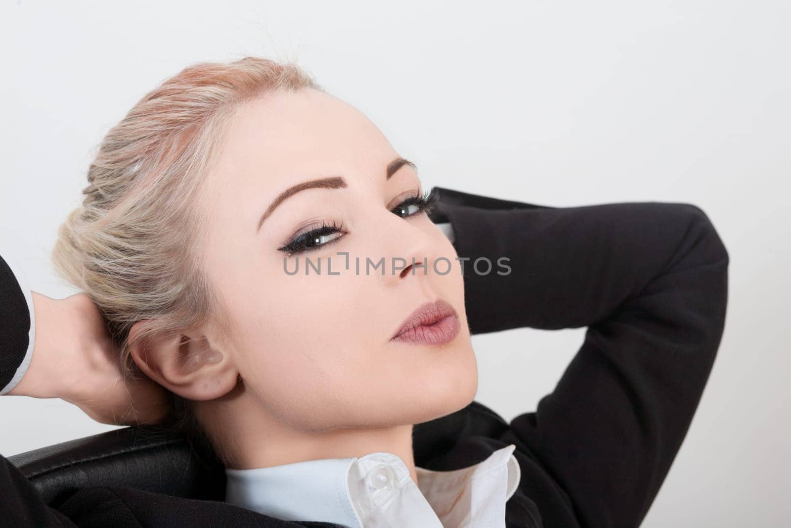 Businesswoman is taking a break from work, leaning back in her chair with her hands behind her head and a thoughtful expression