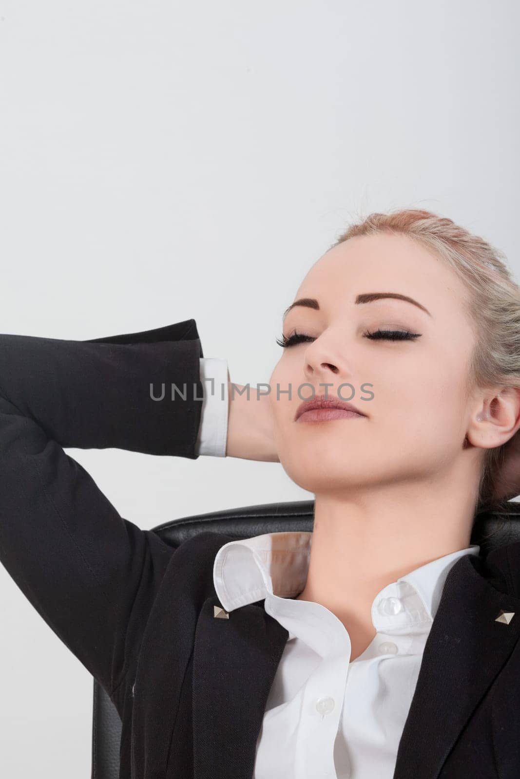 Businesswoman taking a break from work, relaxing with eyes closed and hands behind her head, exuding calm and peace. Reflecting on work life balance and mindfulness for wellbeing