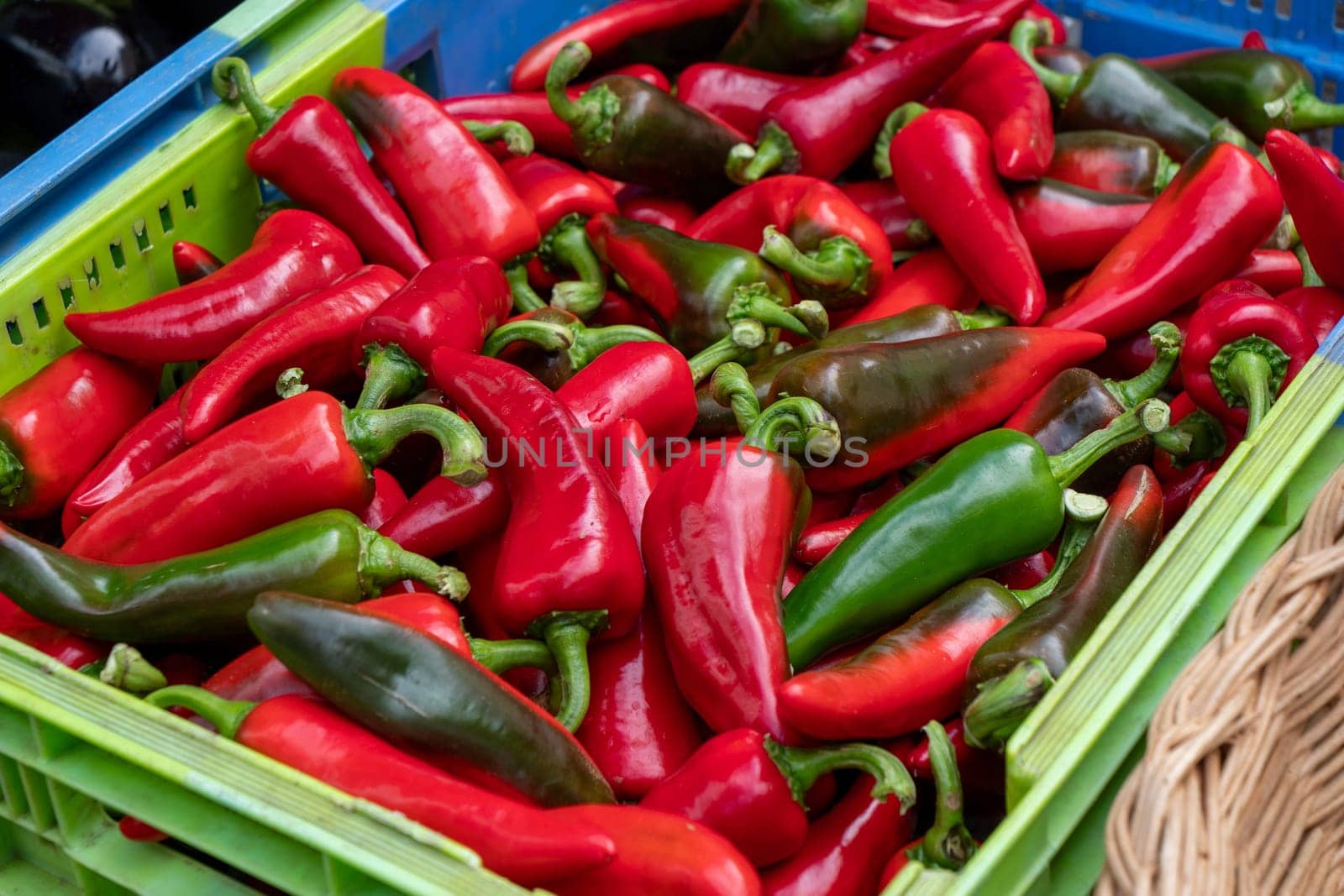A green and red pepper basket with many peppers