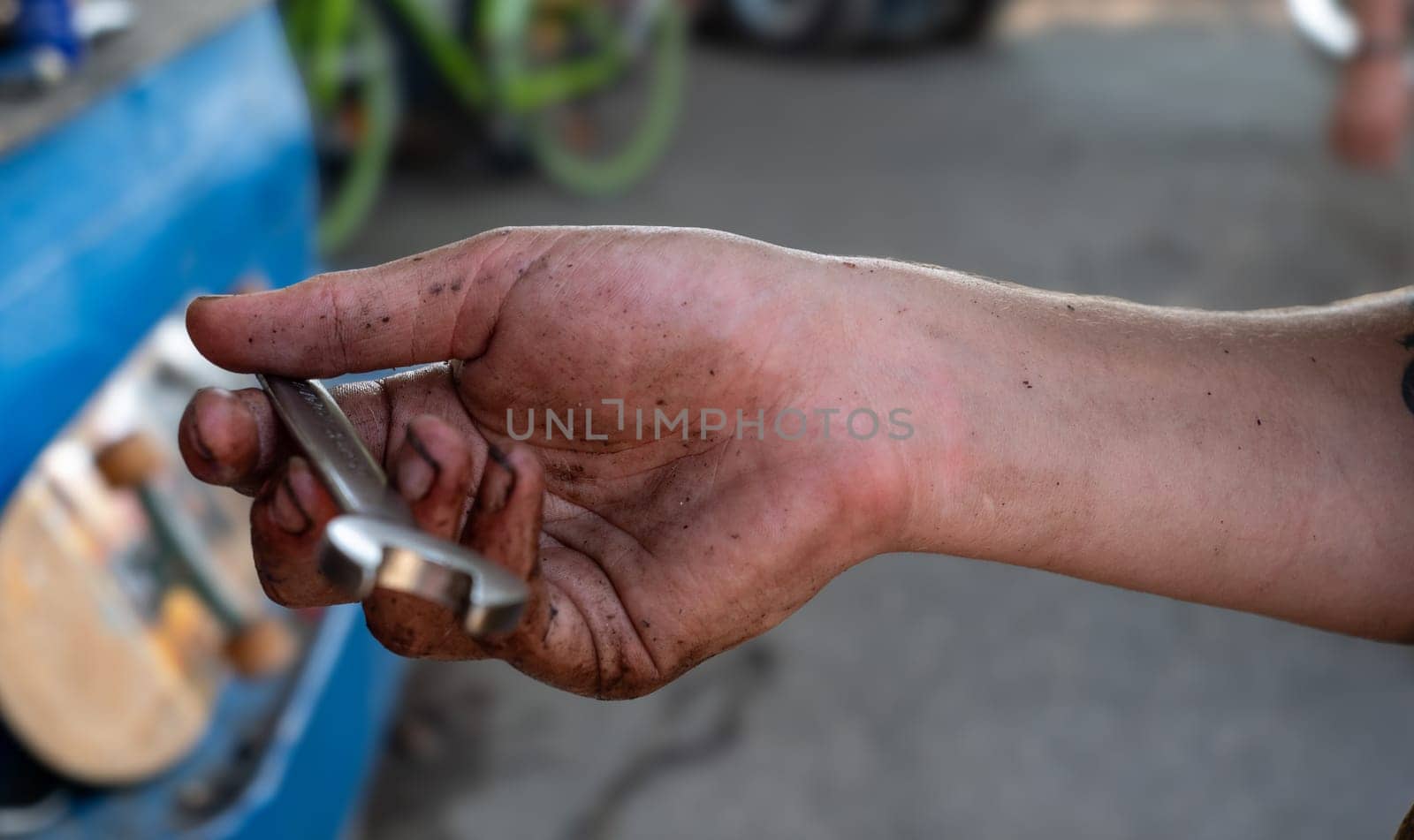 A man's hand is holding a wrench with dirt on it. Concept of hard work and manual labor