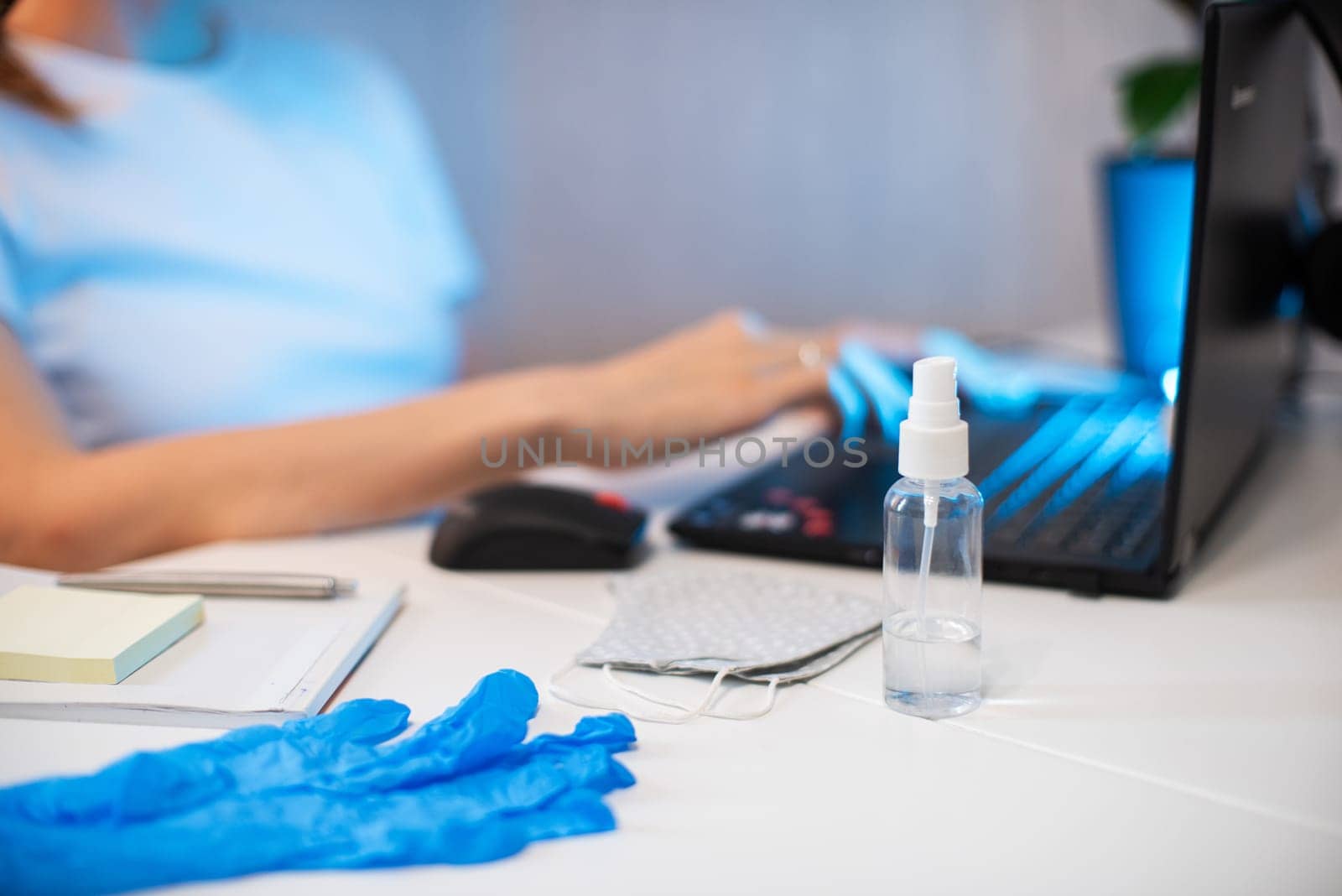 Woman working with notebook. Protective mask and Sanitizer spray on the working place