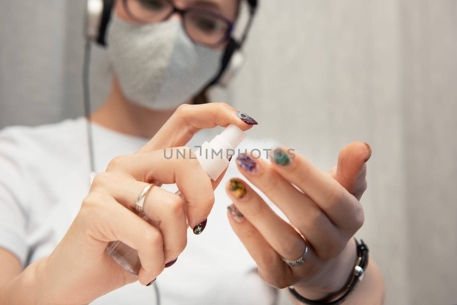 Woman disinfects the surface of the phone by sanitizer spray on the working place. Coronavirus concept. Woman in quarantine for coronavirus covid-19 working from home.