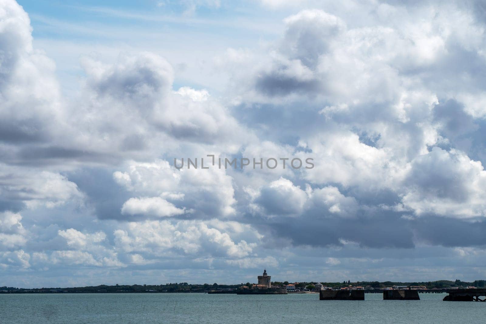 The sky is cloudy and the water is calm. The clouds are low and the water is blue