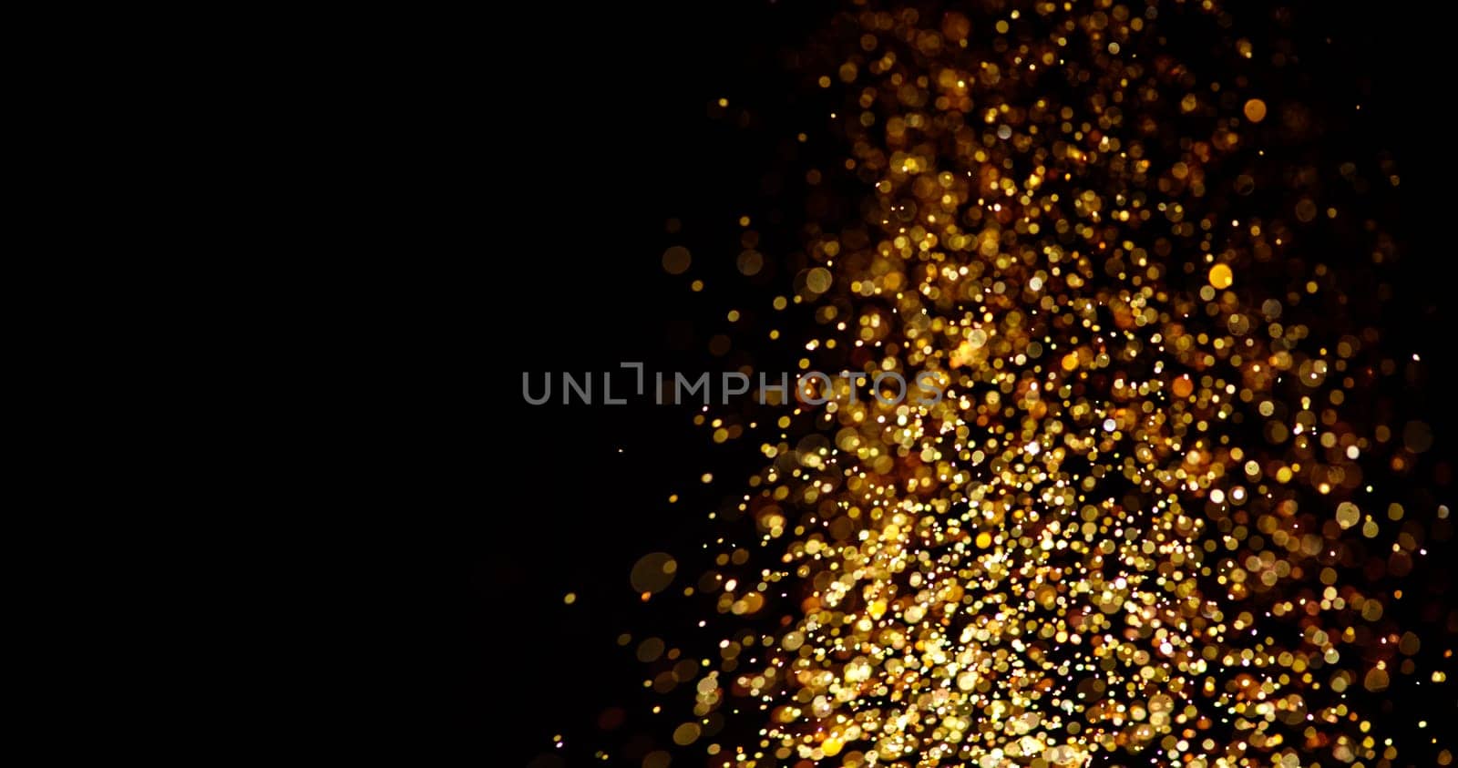 Gold glitter stardust trail on black background. Christmas golden spark border with space. Luxury new year holidayparty bokeh splash design.