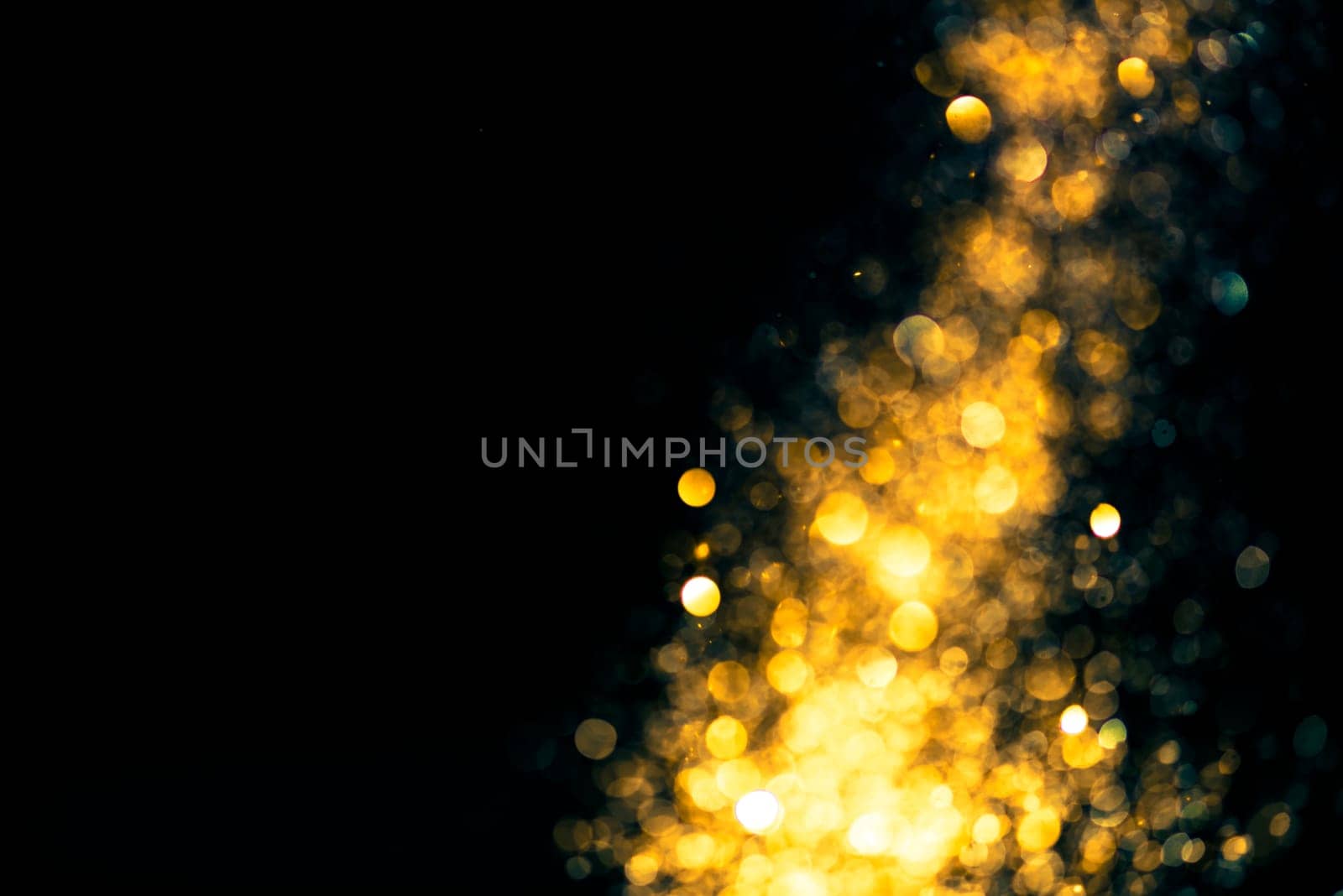 Gold glitter stardust trail on black background. Christmas golden spark border with space. Luxury new year holidayparty bokeh splash design.