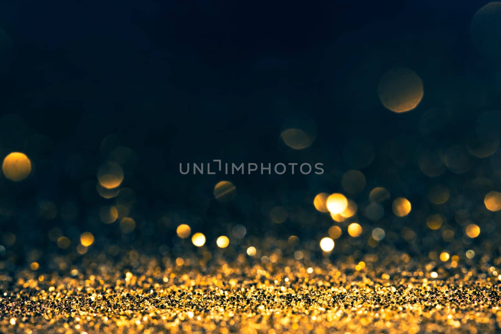Luxury abstract glitter bokeh background. New year and christmas holiday party design. Golden star dust light sparkling on dark backdrop.