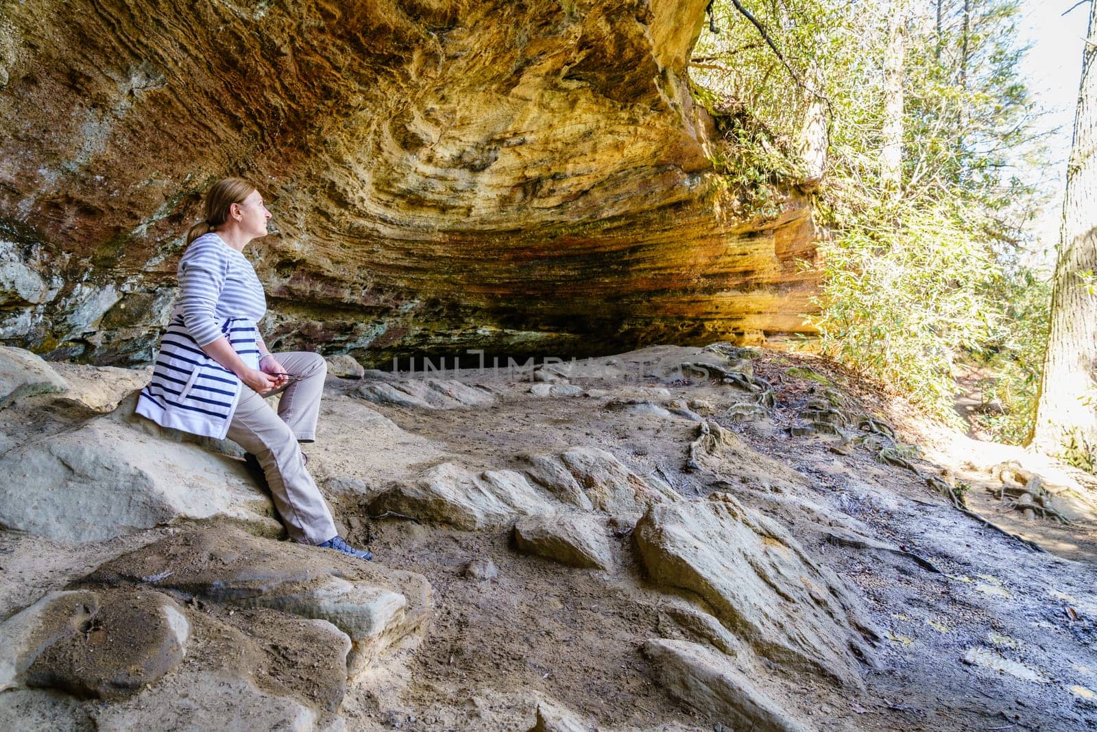 Female hiker taking rest in a small grotto in Red River Gorge in Kentucky