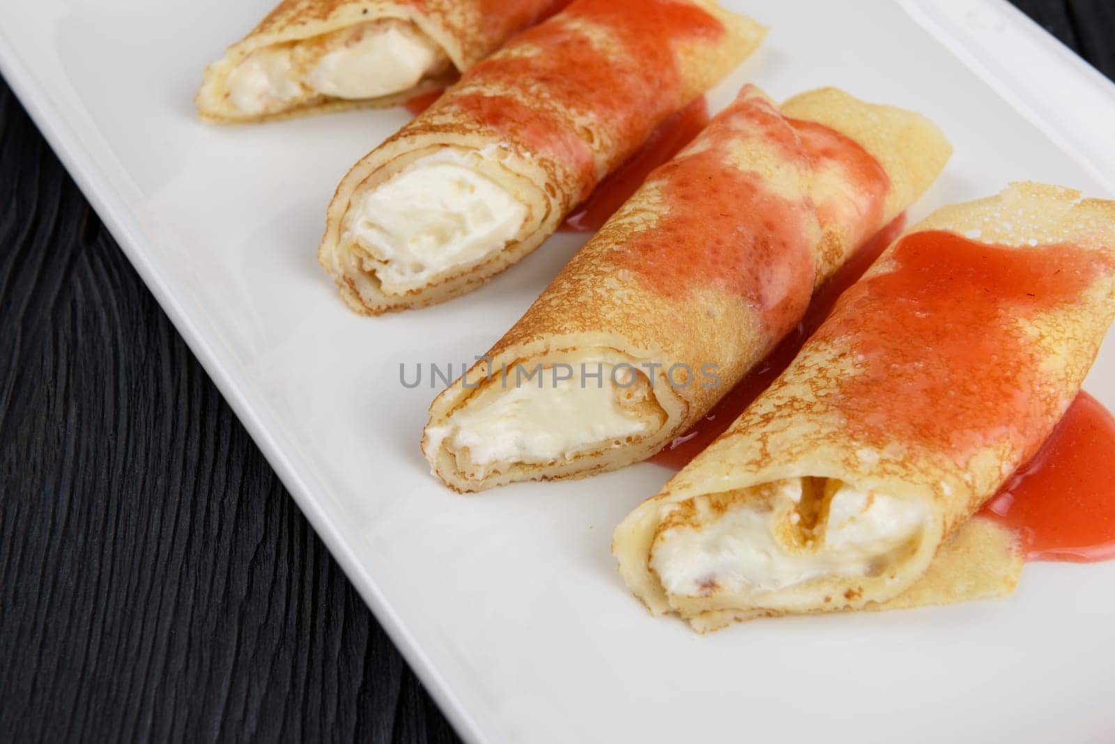 Pancakes or russian blini stuffed with cream sauce on a white plate.