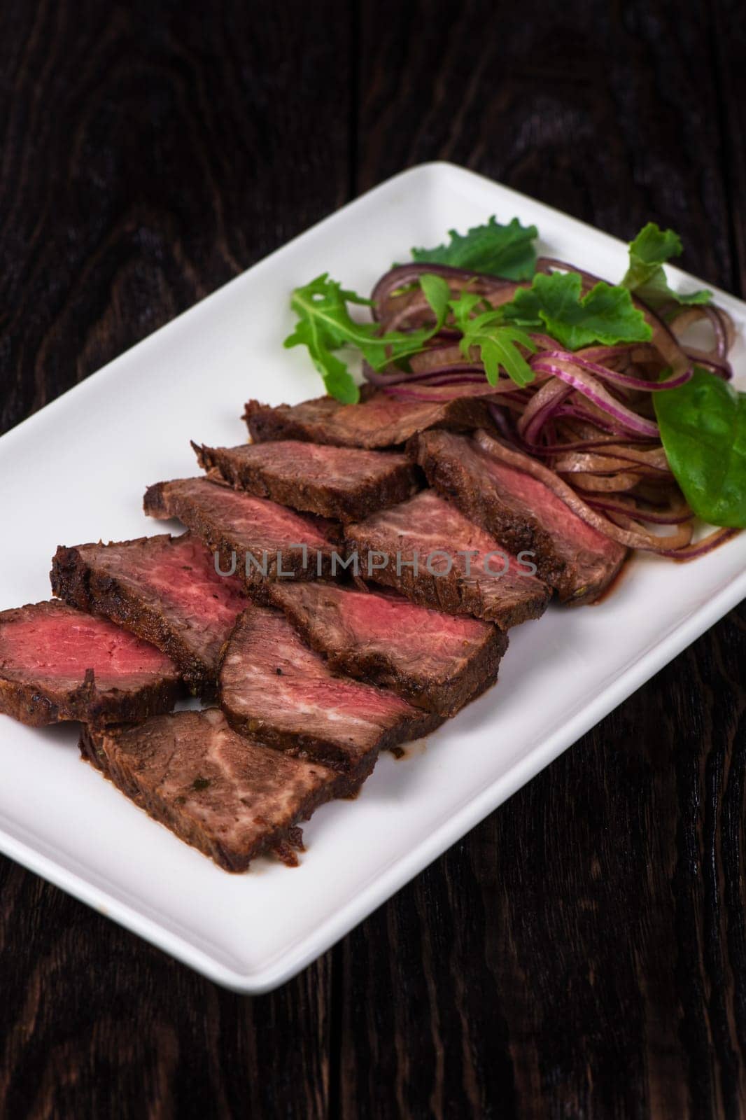 Plate with meat cutting and fresh greens on white plate