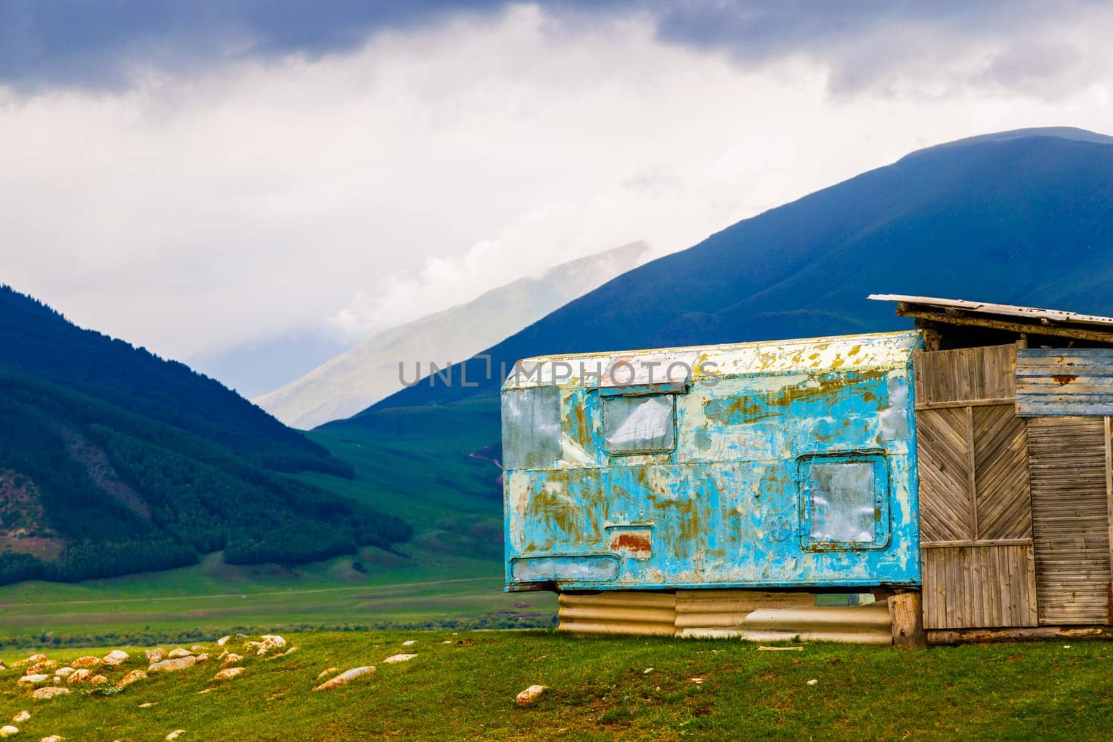 shabby mountain cabin made of old truck bed camper at summer day