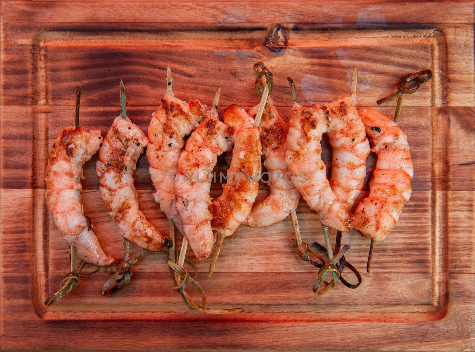 A professional cook prepares shrimps on the grill outdoor, food or catering concept