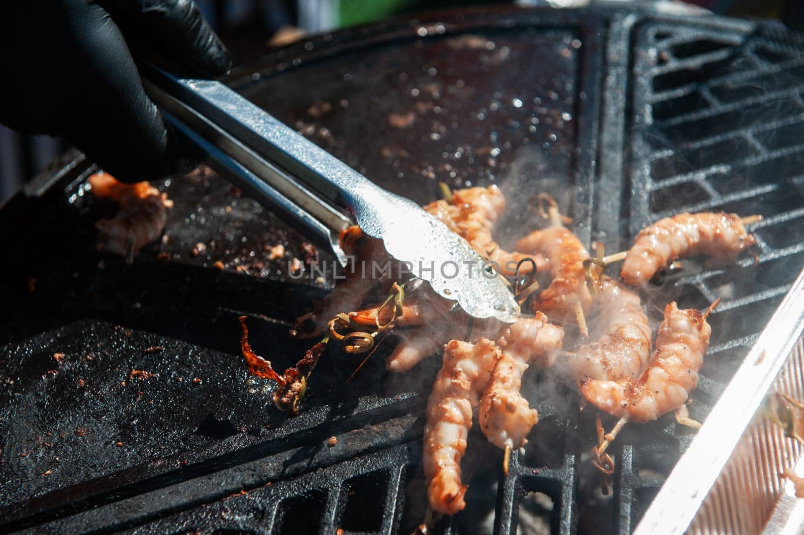 A professional cook prepares shrimps on the grill outdoor, food or catering concept