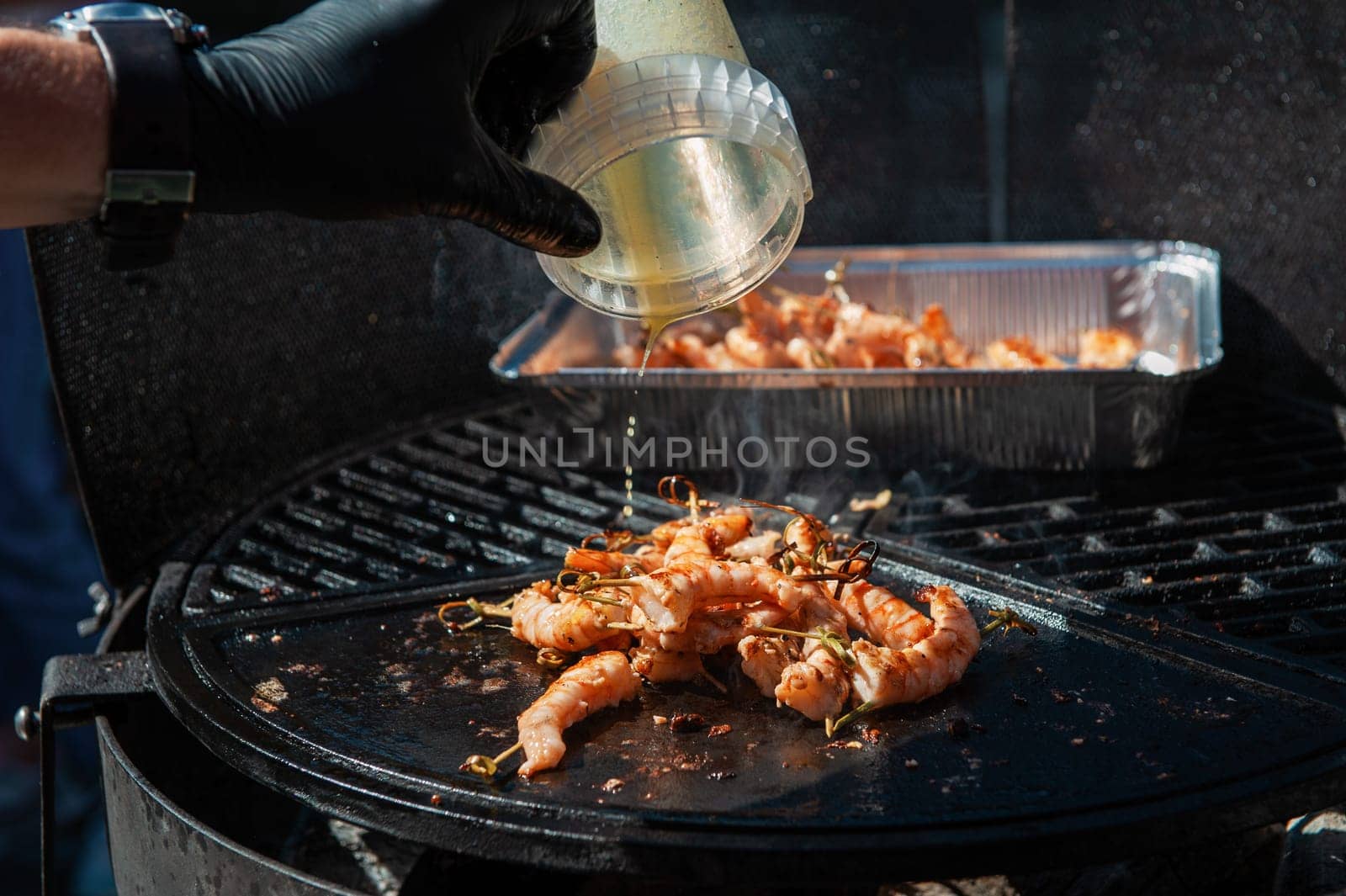 A professional cook prepares shrimps on the grill outdoor, food or catering concept