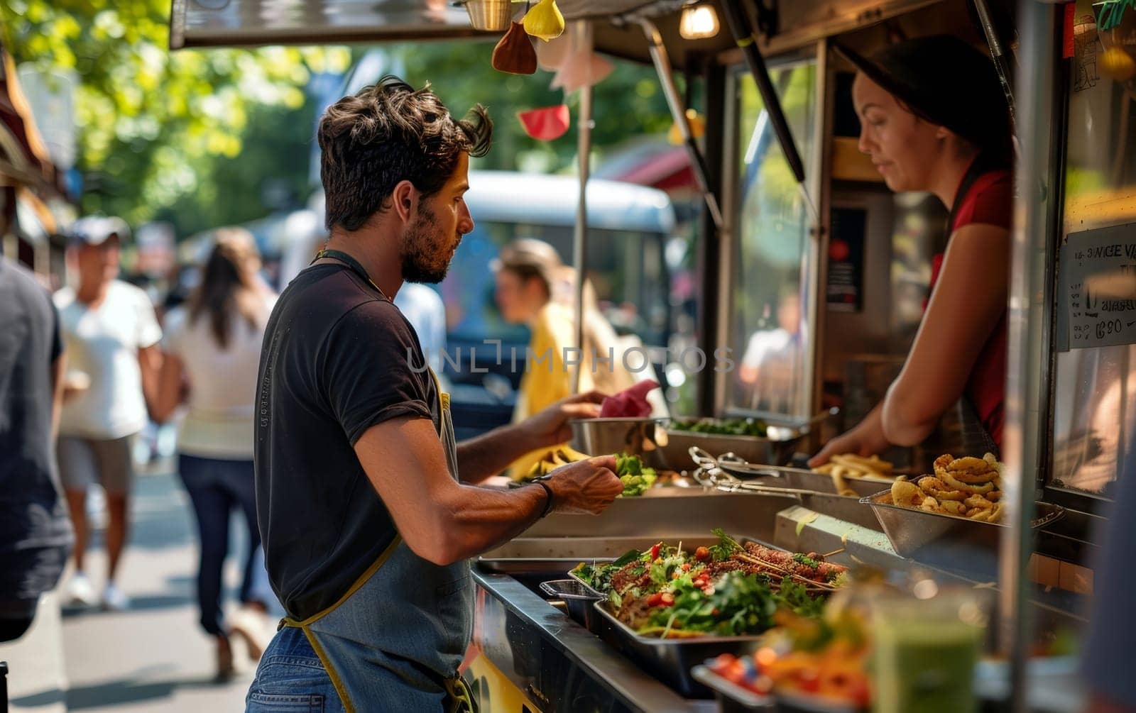 A man orders at a food truck on a sunny day, surrounded by a bustling crowd and vibrant street food options