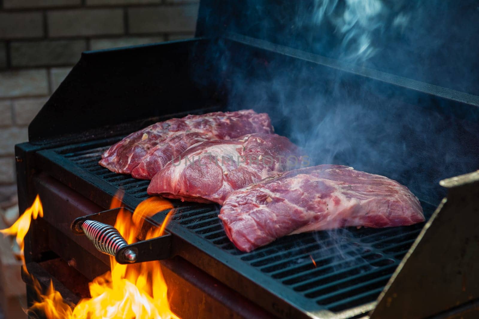 Pork meat steaks on the grill with flames