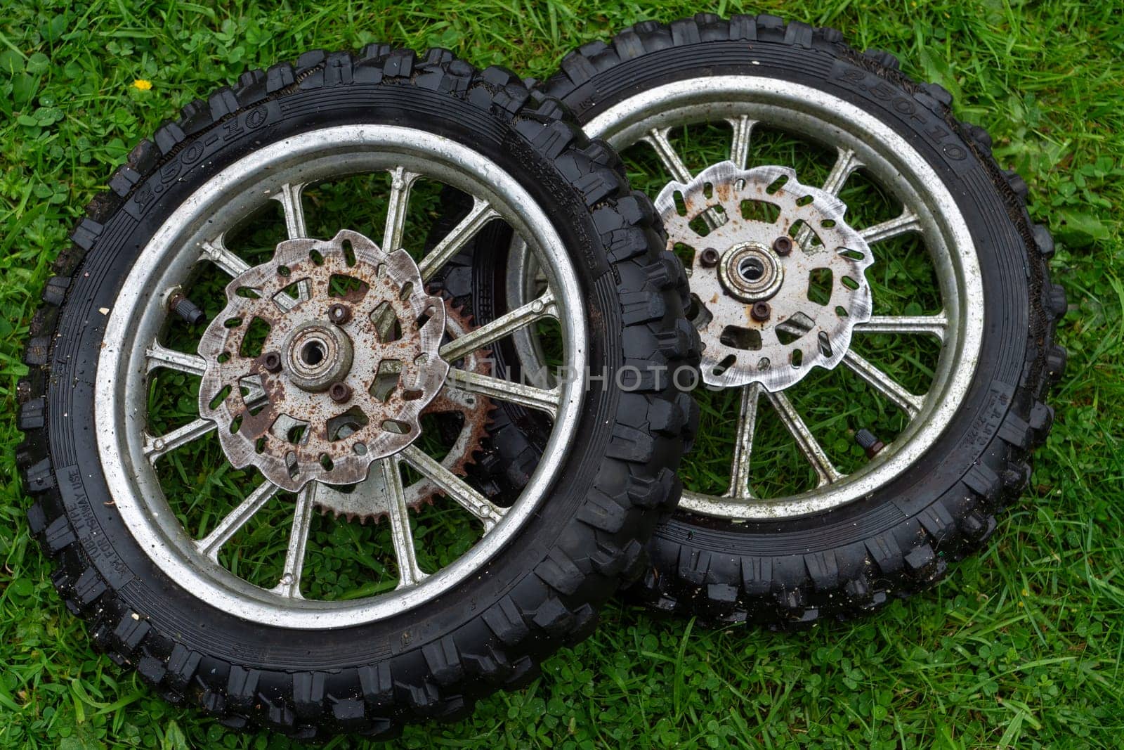 Two tires are on the grass, one of which is missing a spoke. The other tire has a spoke missing