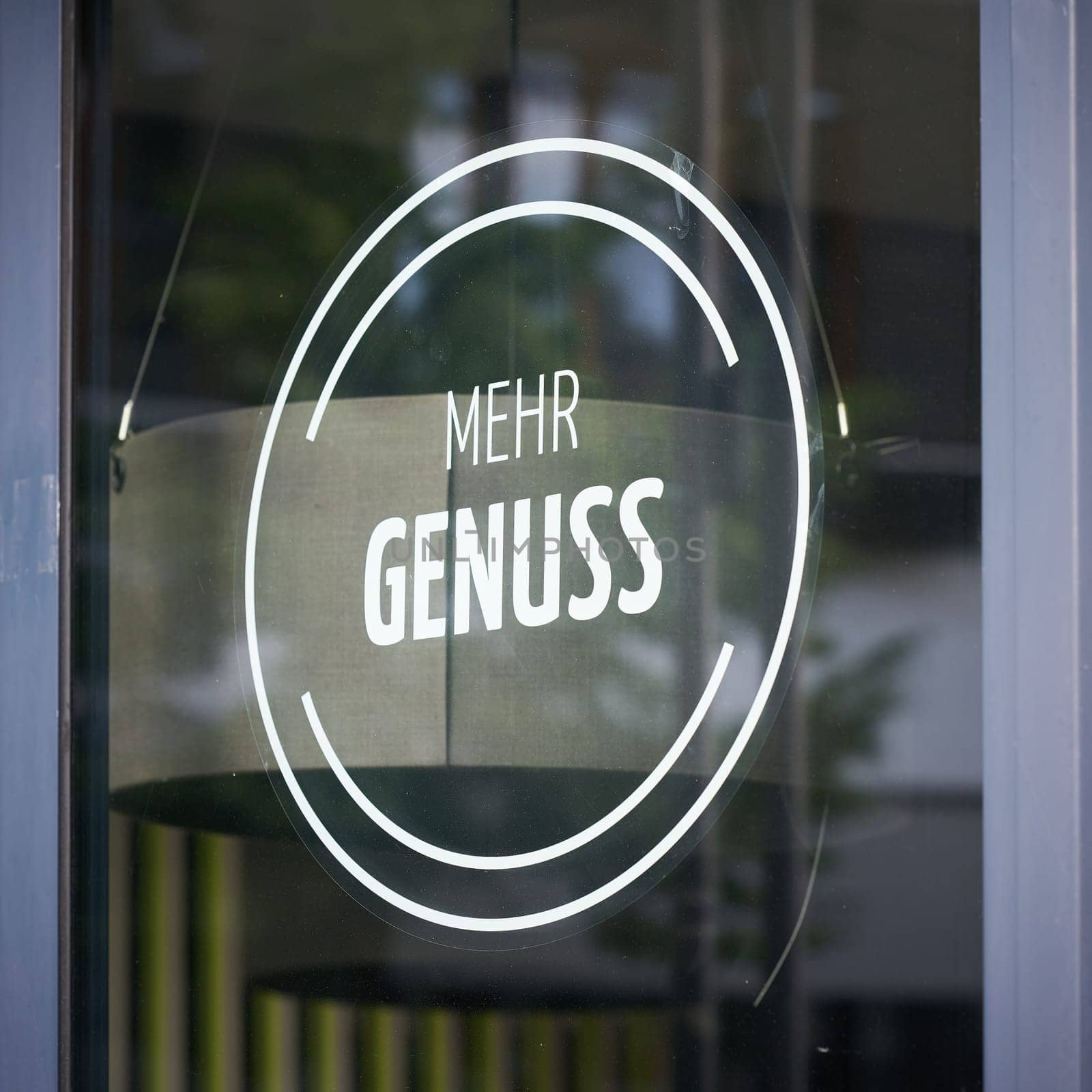 Sticker on the window of a store with the German inscription mehr Genuss. Translation: more pleasure