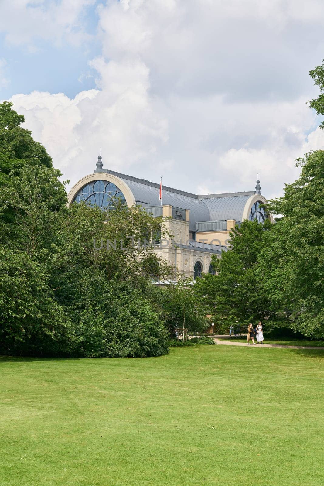 Cologne, Germany – May 20, 2024: View across a meadow to the Flora building, the botanical garden in Cologne