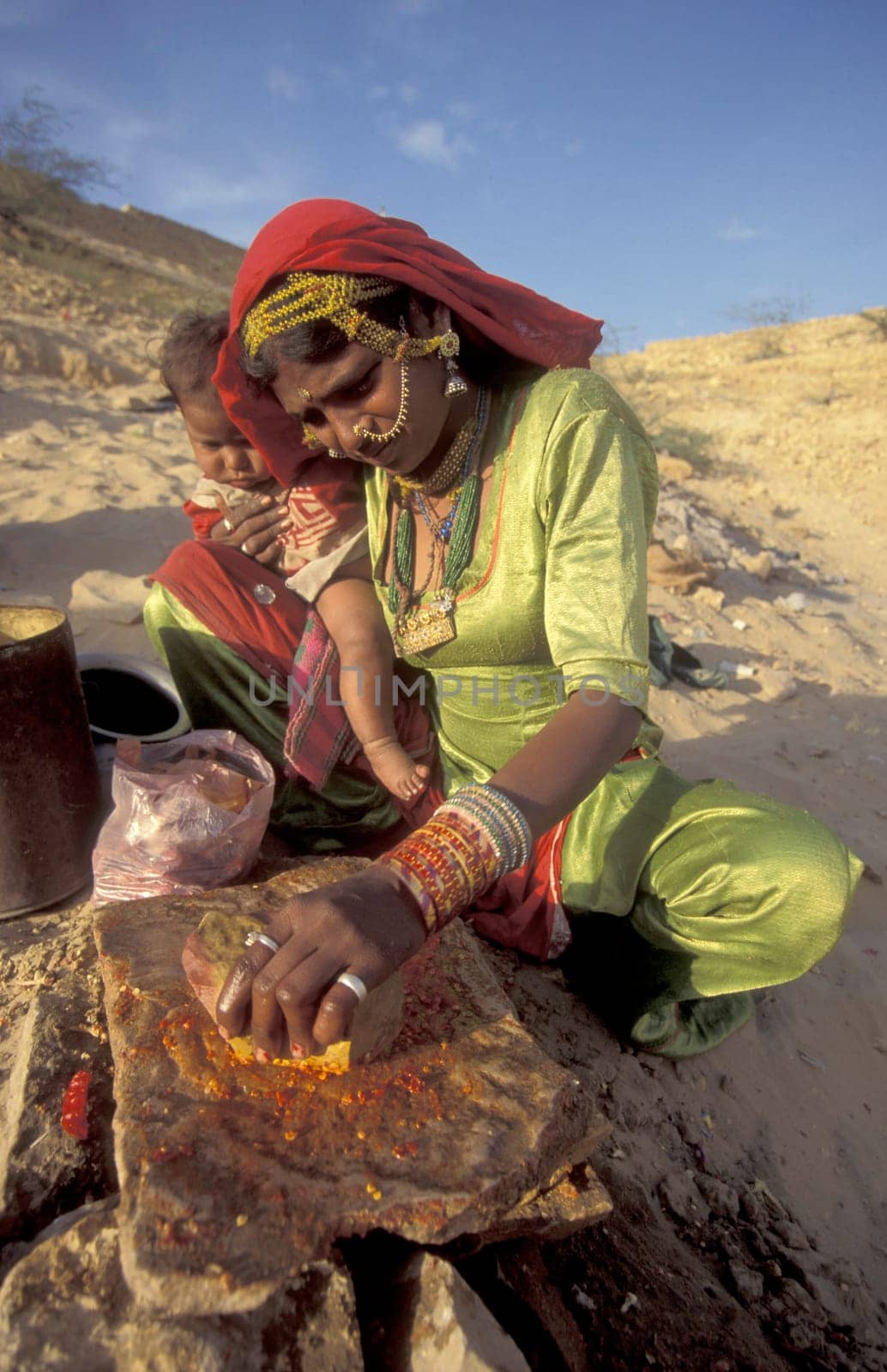 a Rajasthani women is cocking on a fire with her Baby in the Town of Jaisalmer in the Province of Rajasthan in India.  India, Jaisalmer, January, 1998
