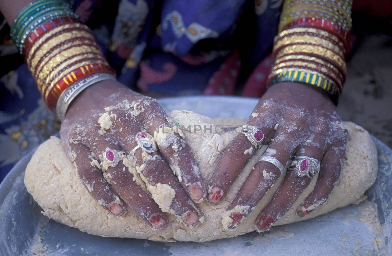 a Rajasthani women is cocking and bake a bread on a fire with her Baby in the Town of Jaisalmer in the Province of Rajasthan in India.  India, Jaisalmer, January, 1998