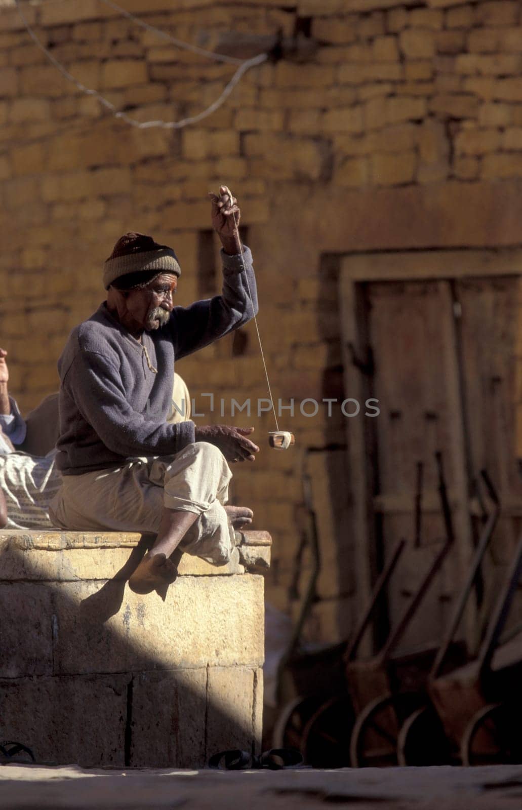a men at spinning thread in alley in the Old Town of Jaisalmer in the Province of Rajasthan in India.  India, Jaisalmer, January, 1998