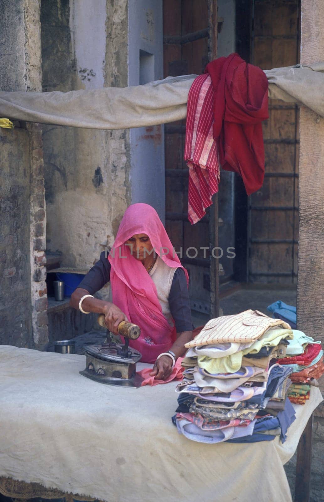 a Rajasthani women at a Laundry and Tailor shop in the Town of Jaisalmer in the Province of Rajasthan in India.  India, Jaisalmer, January, 1998