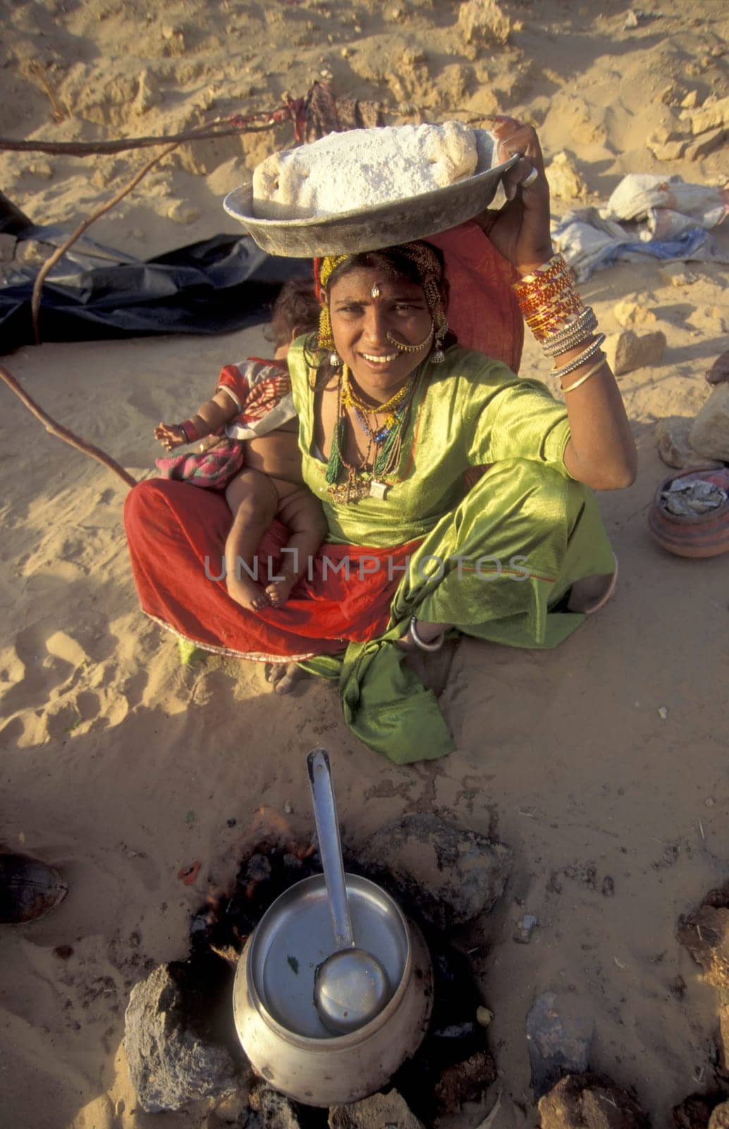 a Rajasthani women is cocking on a fire with her Baby in the Town of Jaisalmer in the Province of Rajasthan in India.  India, Jaisalmer, January, 1998