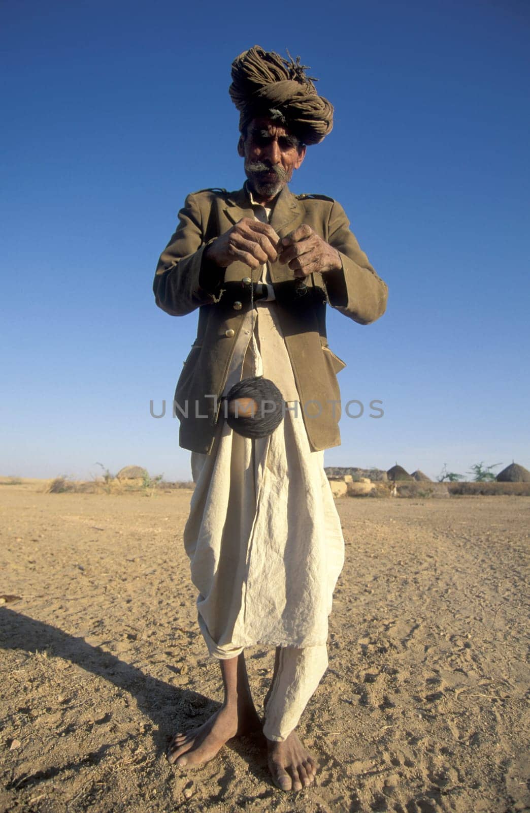 A old Men work with a Cord Spindle in a small Village near the Town of Bikaner in the Desert Thar in the Province of Rajasthan in India.  India, Bikaner, January, 1998