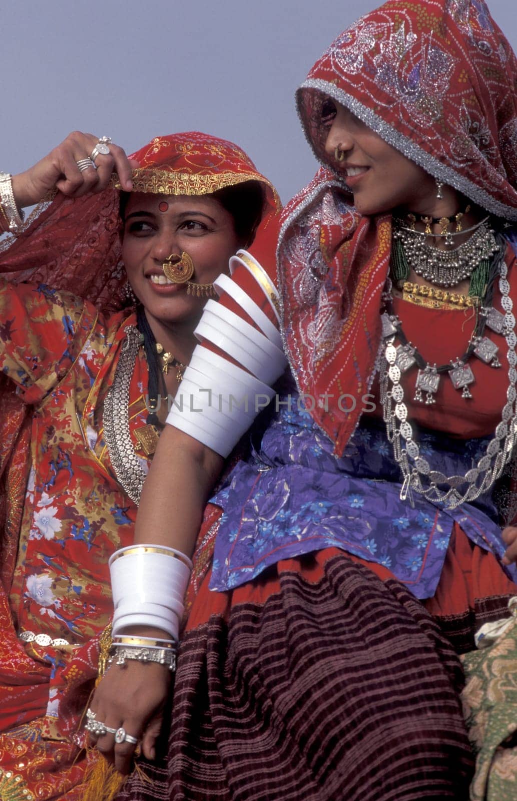 Women in traditional Rajasthani dress on a Camel at the Bikaner Camel Festival in the Town of Bikaner in the Province of Rajasthan in India.  India, Bikaner, January, 1998
