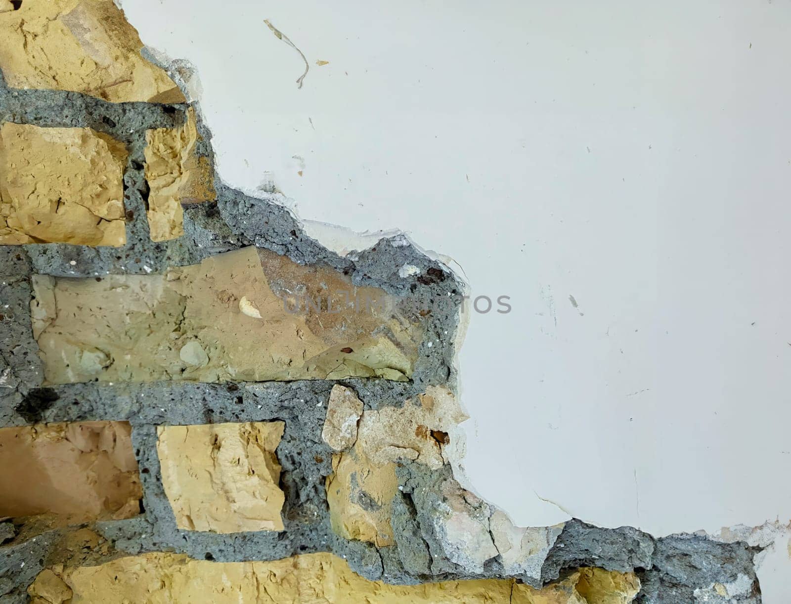Close-up of an exposed brick wall with cracked and peeling plaster, showing the texture and details of the aged surface