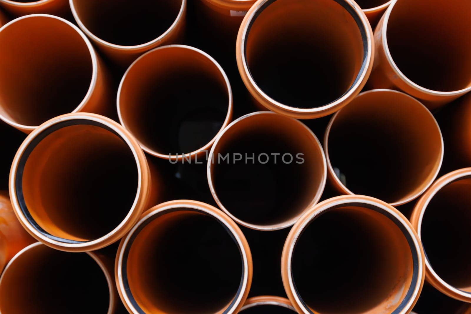 brown plastic plumbing pipes with rubber seals - full-frame closeup background