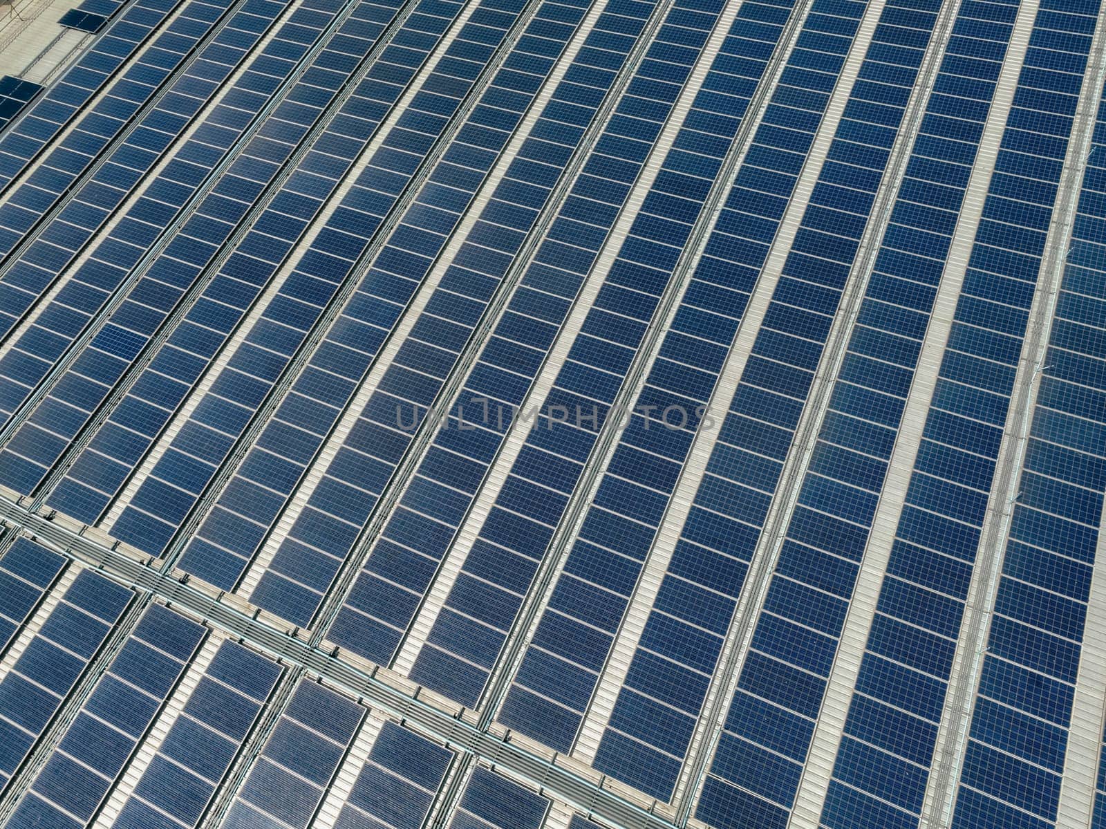 Solar energy for factory and warehouse building. Solar panels on roof of industrial plant. Commercial solar power. Rooftop solar power. Rooftop renewable energy system. Sustainable green energy.