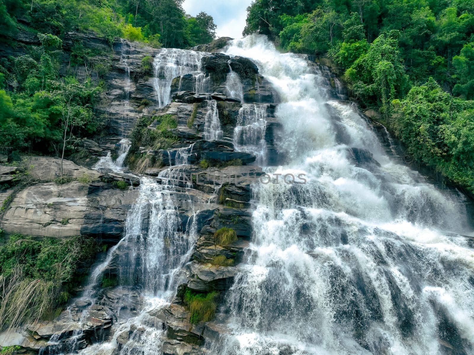 Aerial view of a waterfall in a lush tropical green forest in Doi Inthanon National Park, Chiang Mai, Thailand. This nature landscape showcases water sustainability and scenic travel destinations.