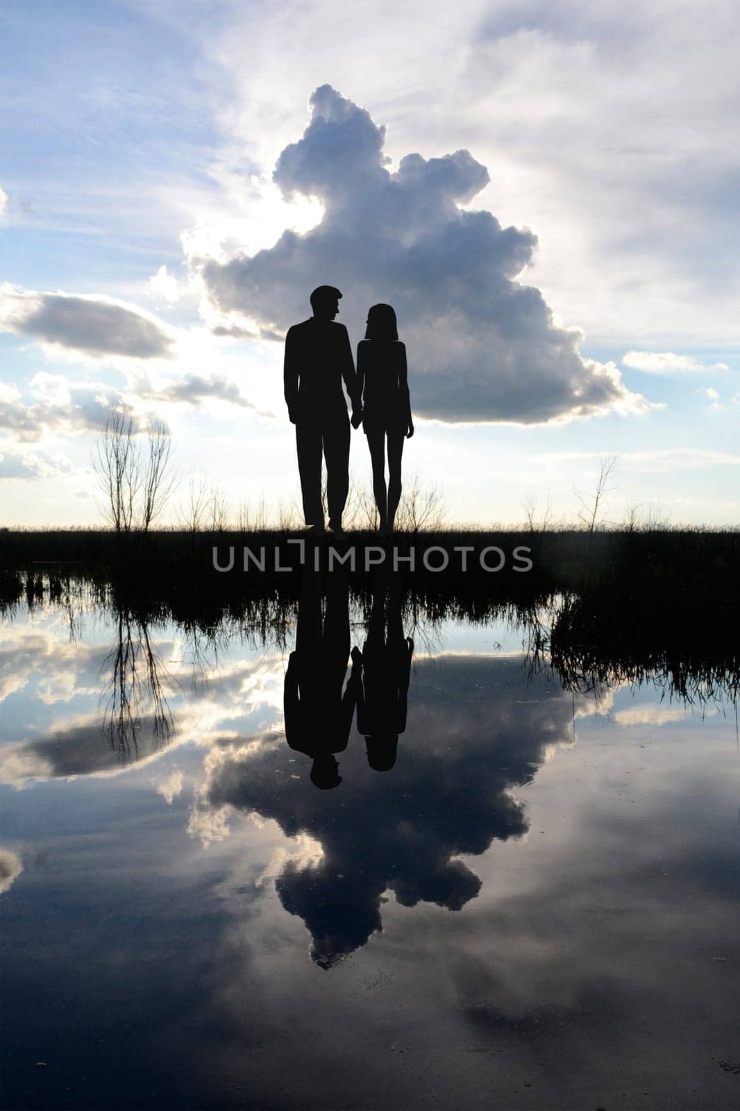 Couple standing on the lake shore with their reflections on the lake