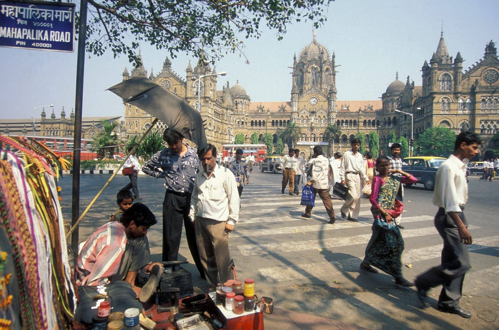 People and Market in front of the architecture of the Mumbai Railway Station or Chhatrapati Shivaji Terminus in the city centre of Mumbai in India.  India, Mumbai, March, 1998