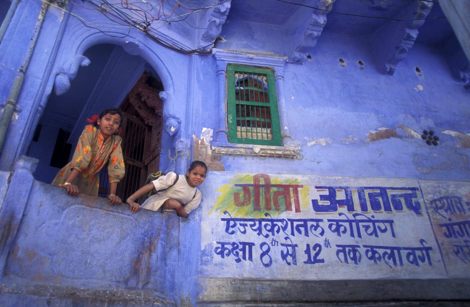 Children at a blue painted living House in the Blue City and Town of Jodhpur in the Province of Rajasthan in India.  India, Jodhpur, January, 1998