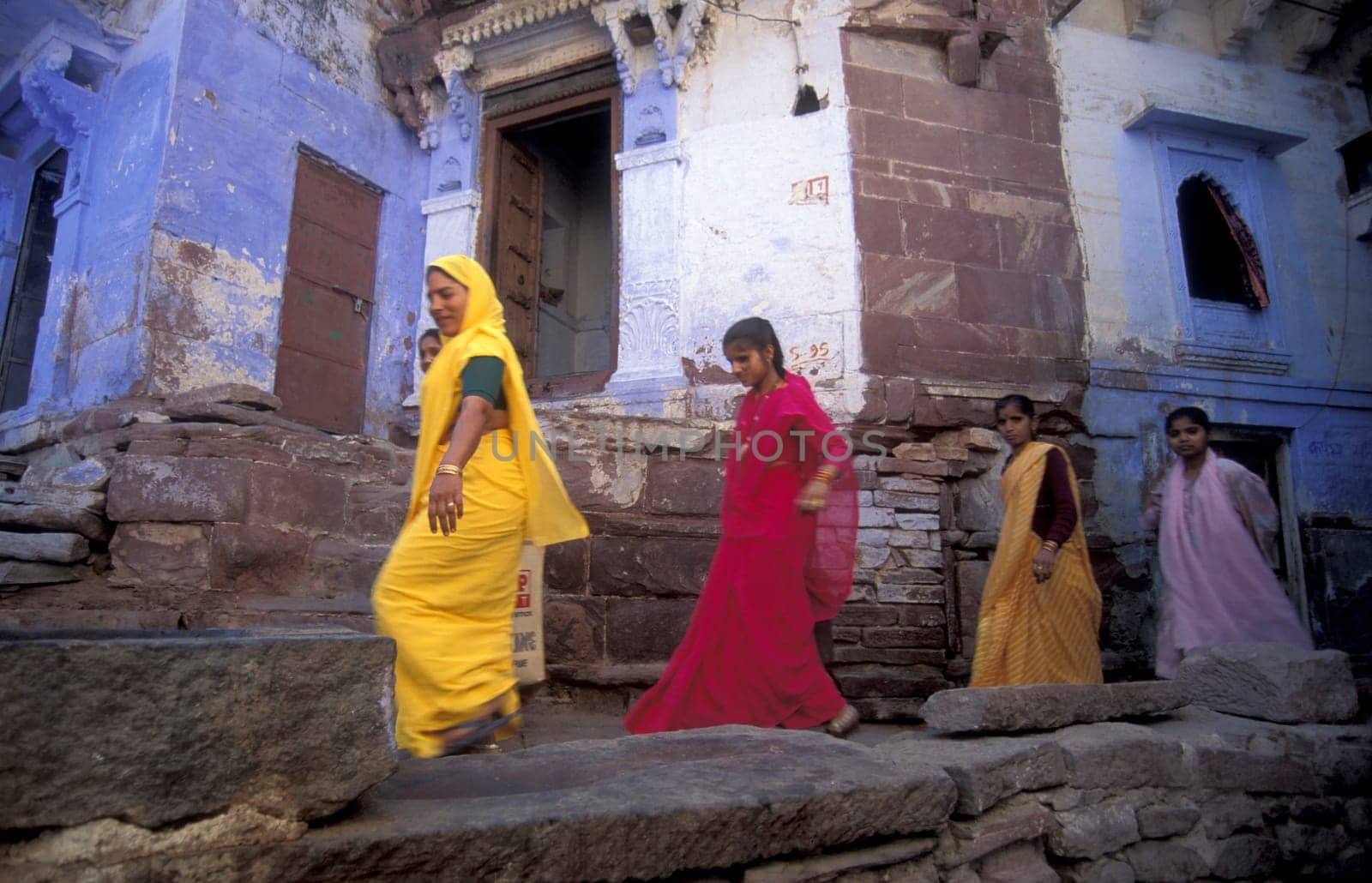 People in a alley with blue painted living House in the Blue City and Town of Jodhpur in the Province of Rajasthan in India.  India, Jodhpur, January, 1998