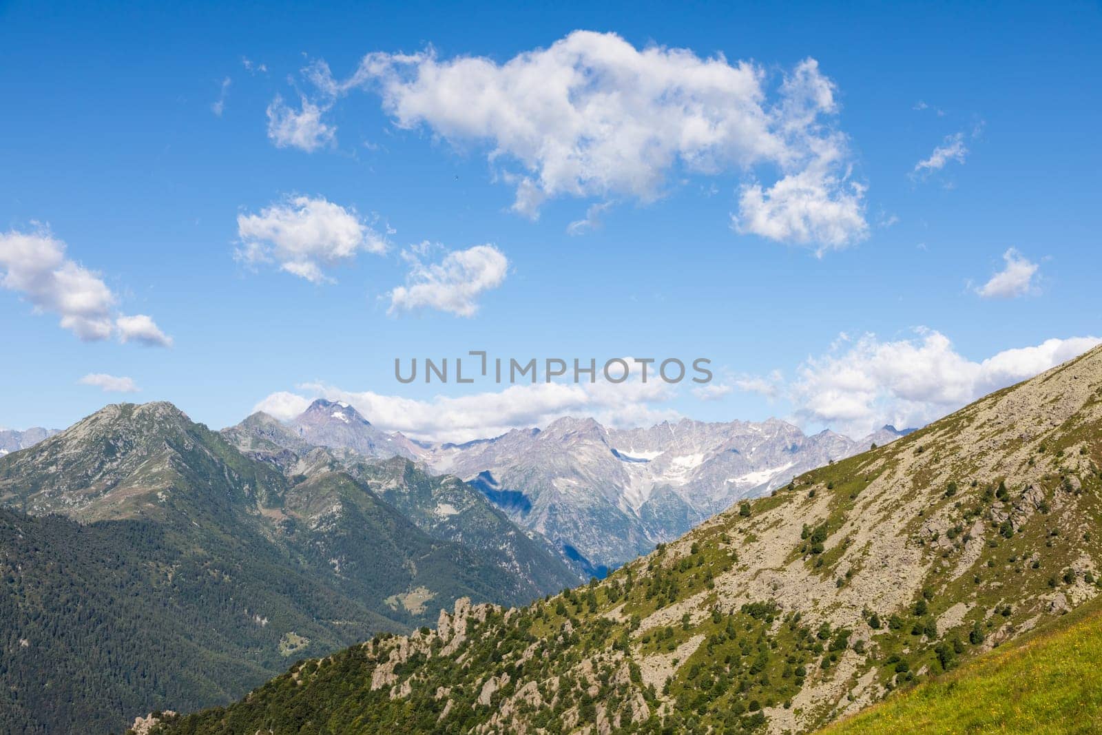 Panorama of Italian Alps with blue sky and clouds. Calm landscape, tranquil scenic view.