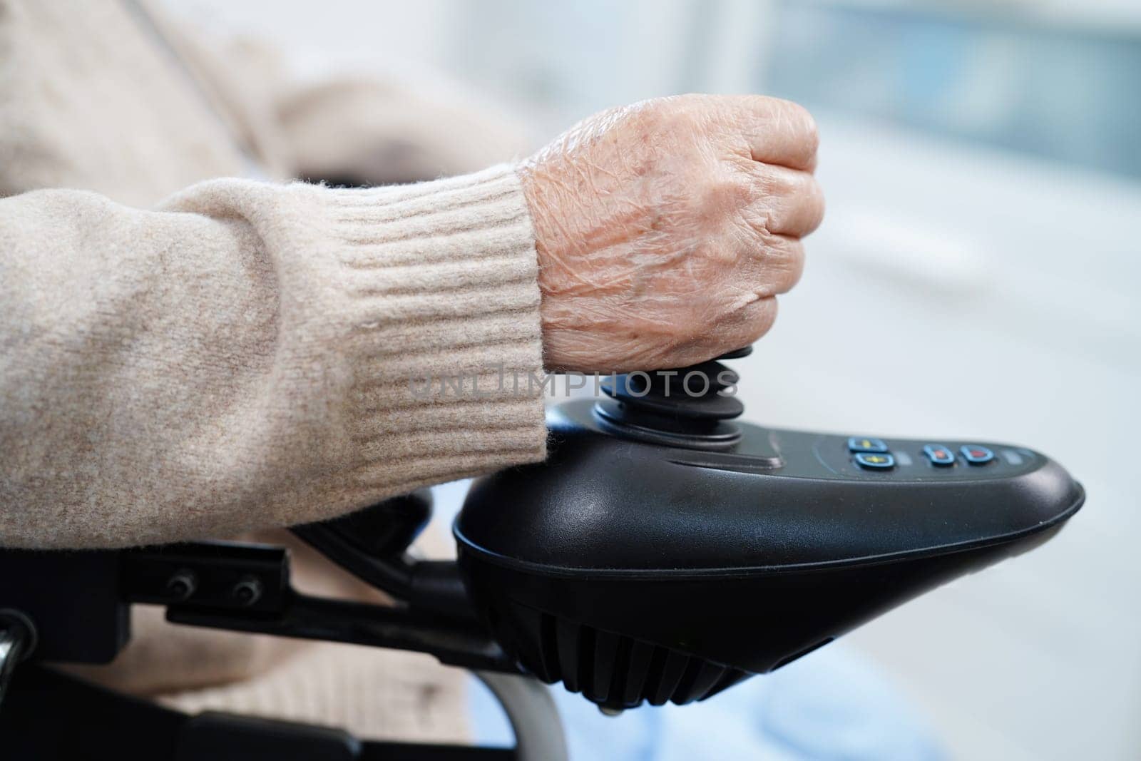 Asian elderly disability woman patient use joystick electric wheelchair in hospital.