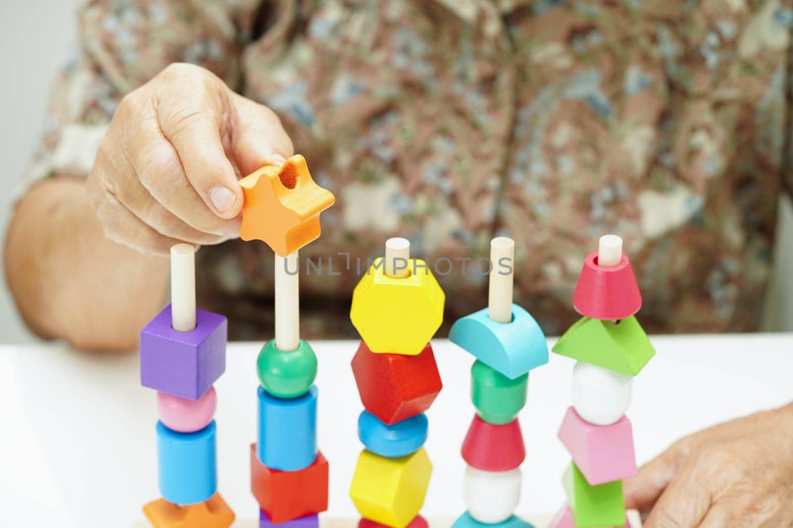 Asian elderly woman playing puzzles game for treatment dementia prevention and Alzheimer disease.