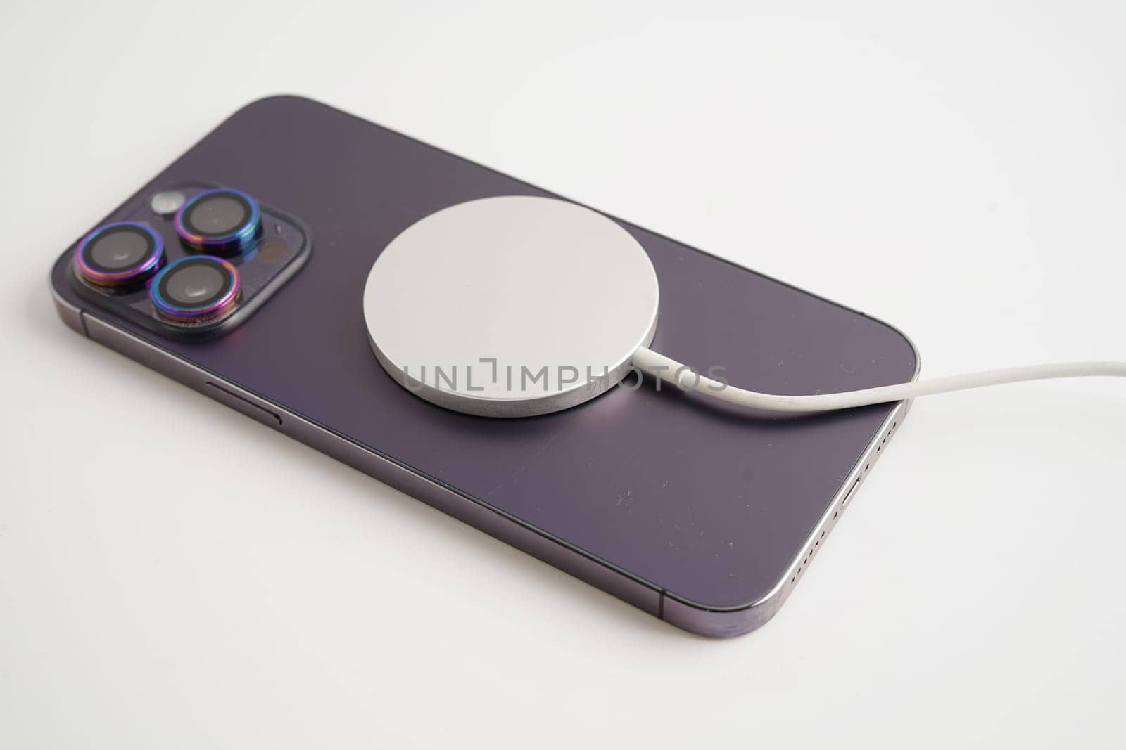 BANGKOK,THAILAND. MARCH 29 2024 MagSafe wireless magnetic charger back of iPhone 14 Pro Max, modern equipment of mobile phone.