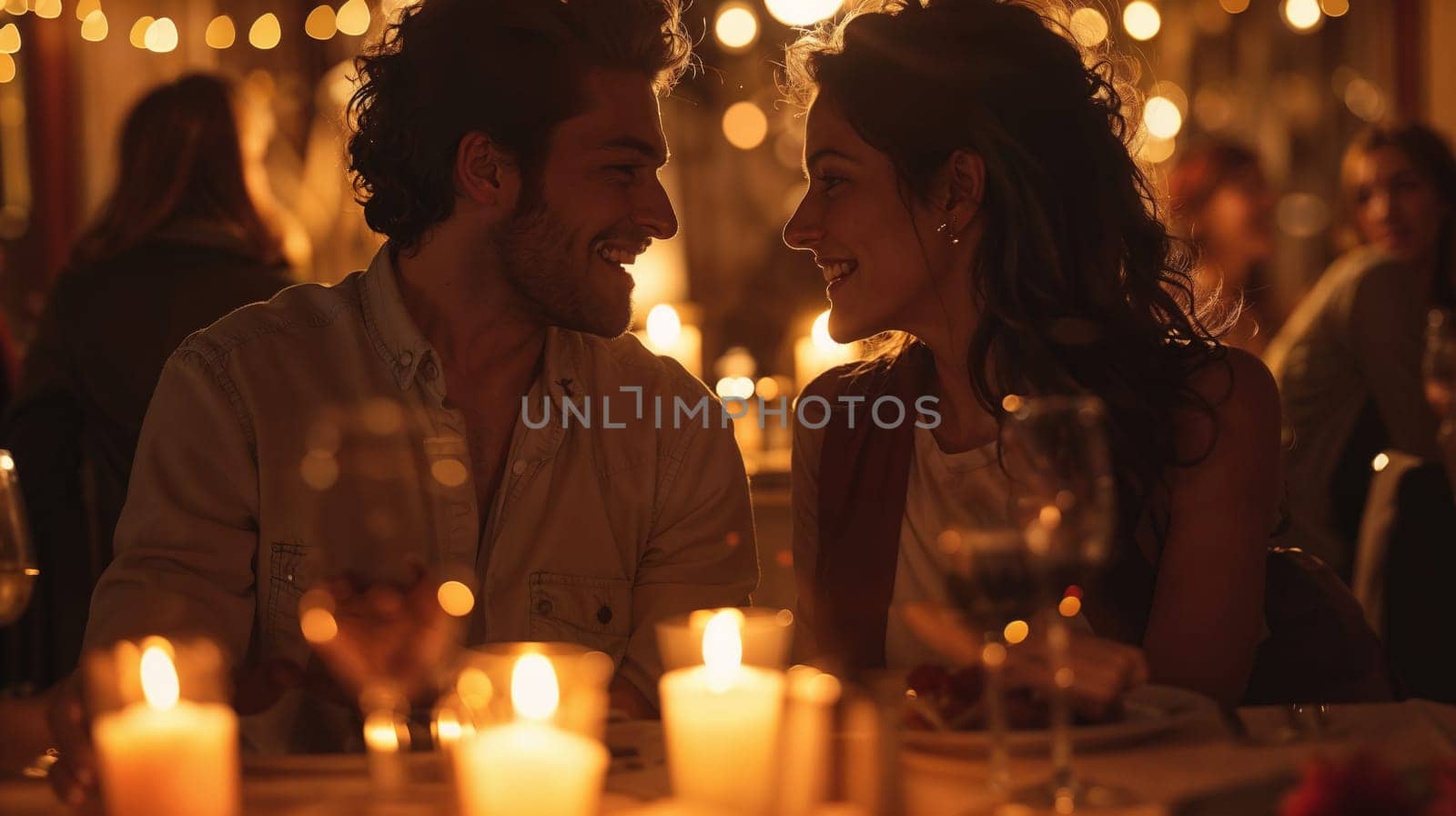 A man and a woman are sitting at a table with candles around them and looking at each other