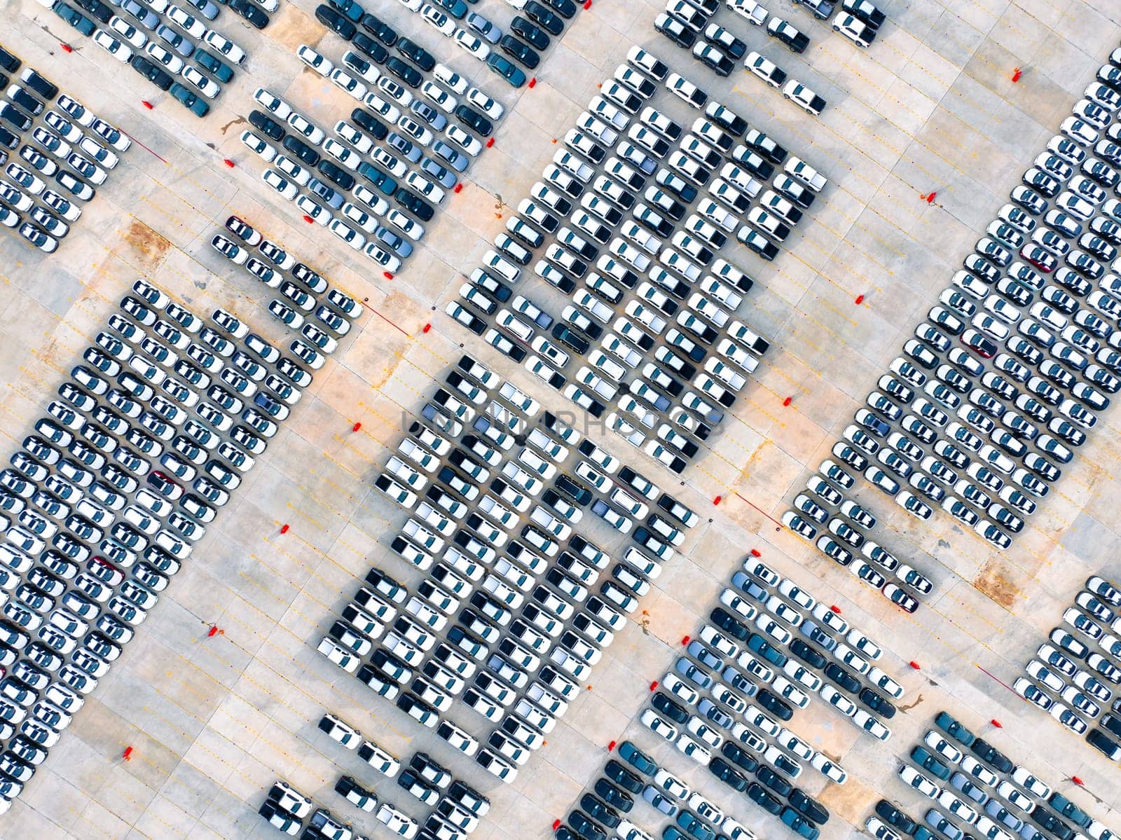 Aerial view of automotive logistics. Factory parking lot filled with rows of new cars. Modern vehicle production and distribution. Import or export operations at expansive port terminal facilities