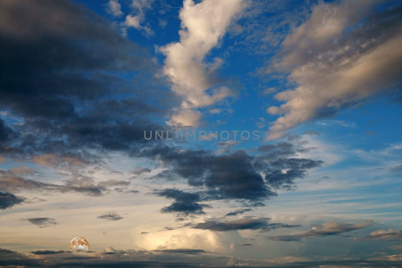 A beautiful summer sunset with a white-blue sky and a rising full moon