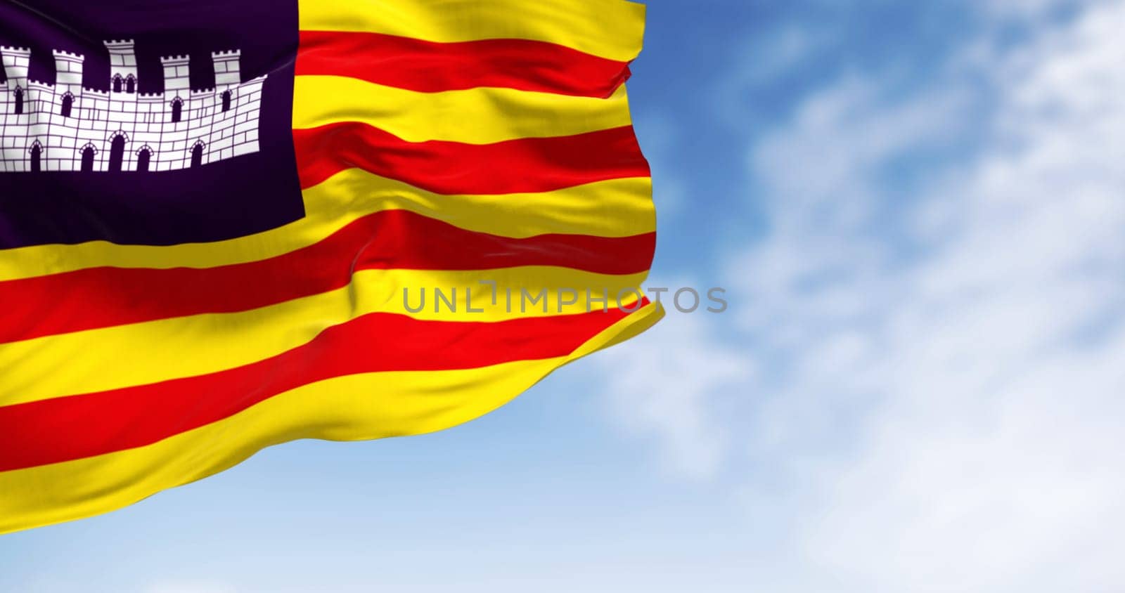 Balearic Islands flag waving in the wind on a clear day. Four red lines on yellow with white castle on purple canton. 3D illustration render. Rippling fabric. Selective focus