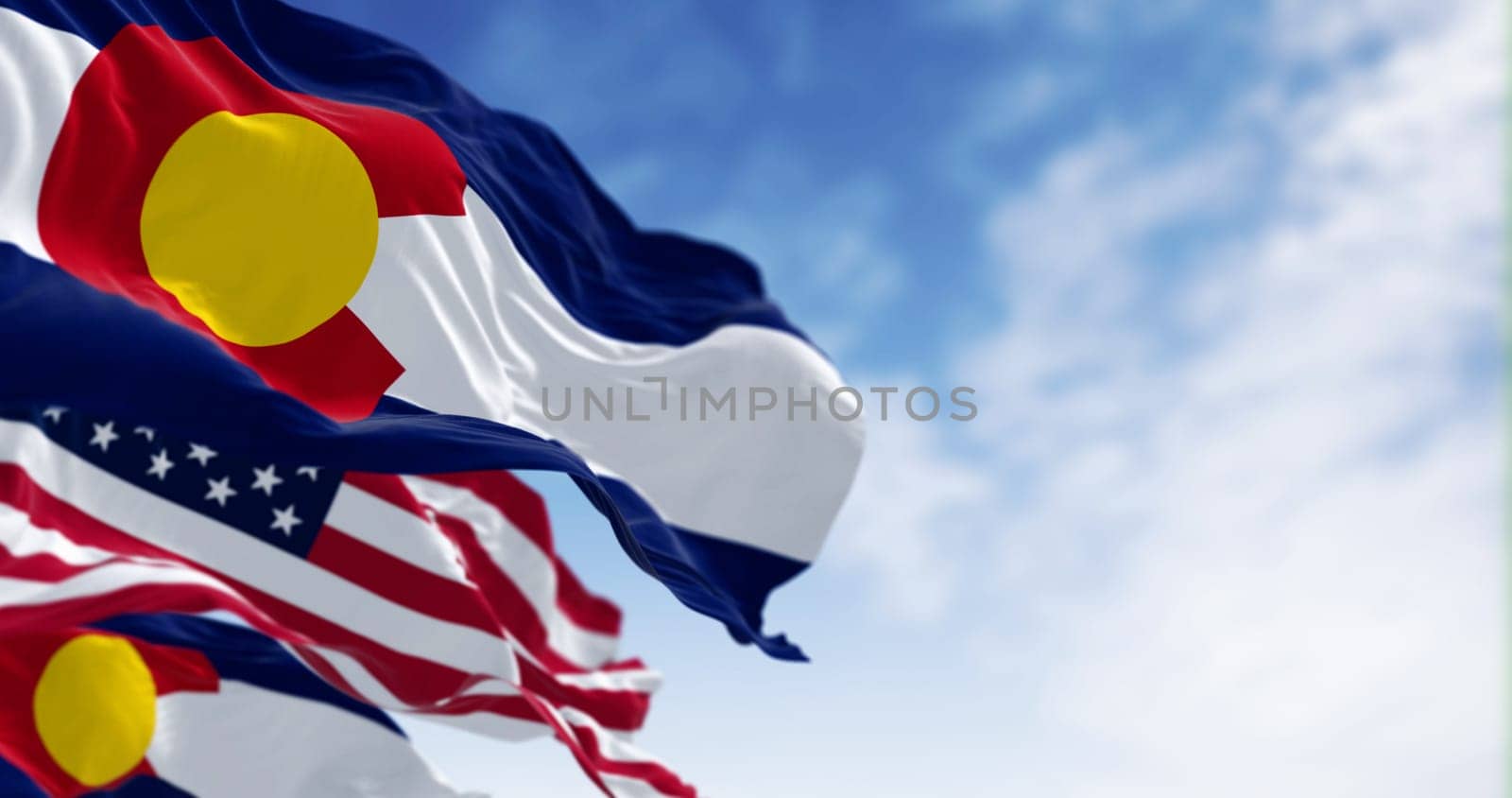 Colorado state flags waving with the national flags of the United States of America on a clear day. 3D illustration render. Rippled textile. Selective focus