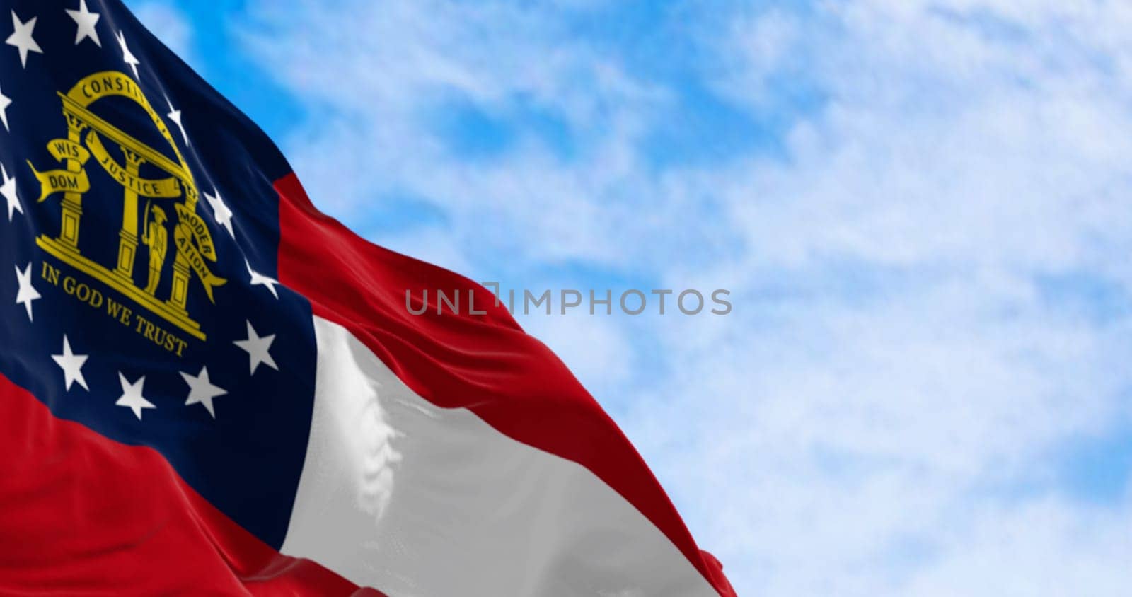 Close-up of Georgia state flag waving in the wind on a clear day. Red, white, red stripes. Blue canton with 13 stars and coat of arms. 3d illustration render. Fluttering textile