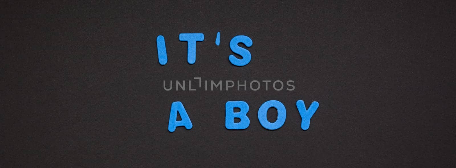 Creative blue text made from plastic letters It's a boy writing on black paper background with copy space. Baby shower concept, celebration card template