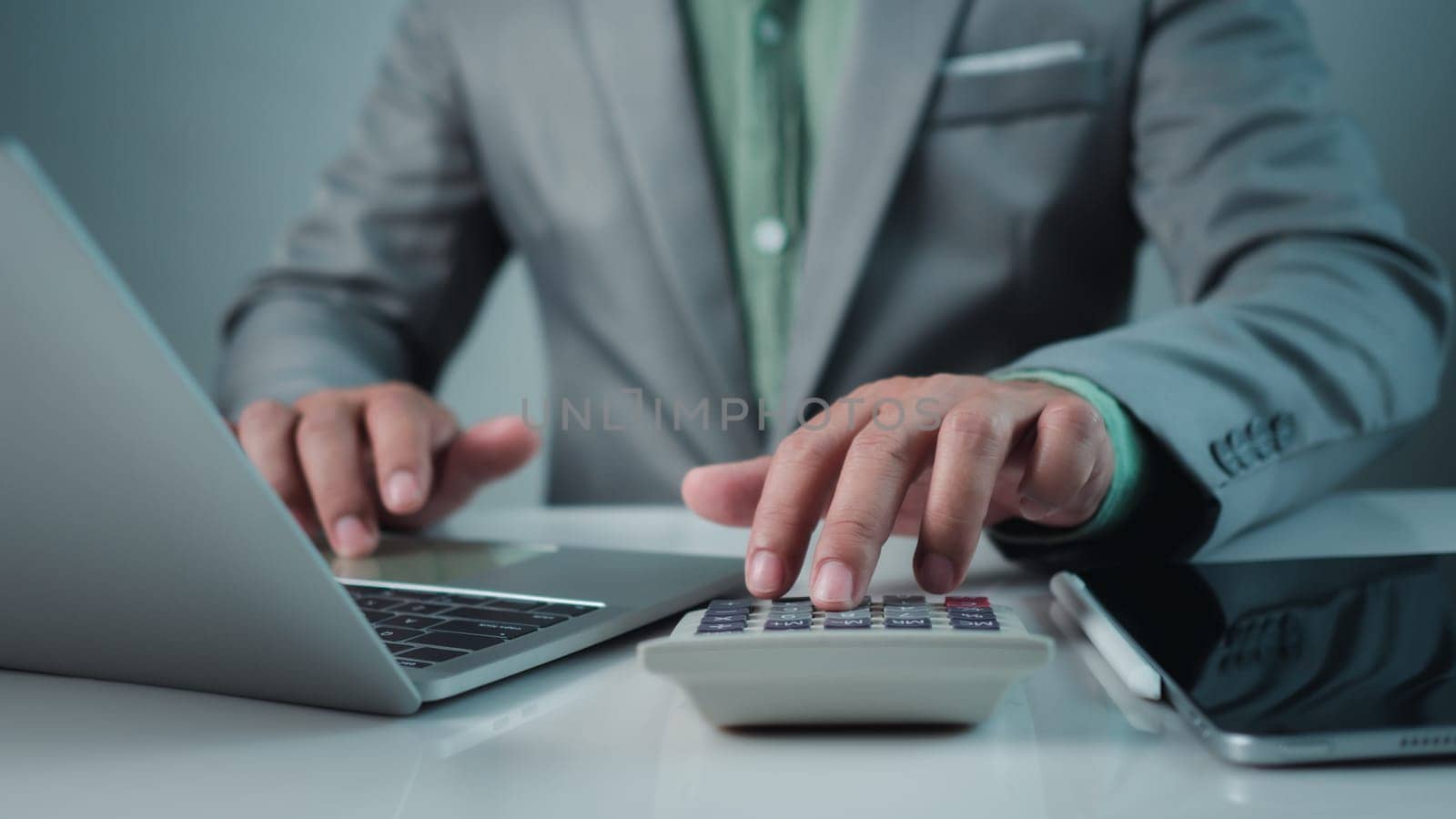 Accountant working with calculator and paperwork, Businessman calculating taxes and finances on laptop at corporate desk, Financial success, Economy concept, Man managing budget and market statistics.