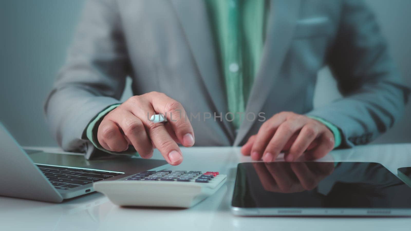 Accountant working with calculator and paperwork, Businessman calculating taxes and finances on laptop at corporate desk, Financial success, Economy concept, Man managing budget and market statistics.